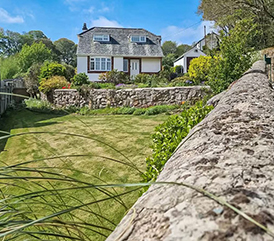 Willow Cottage house with a green garden in the foregrounf and blueskies in the background